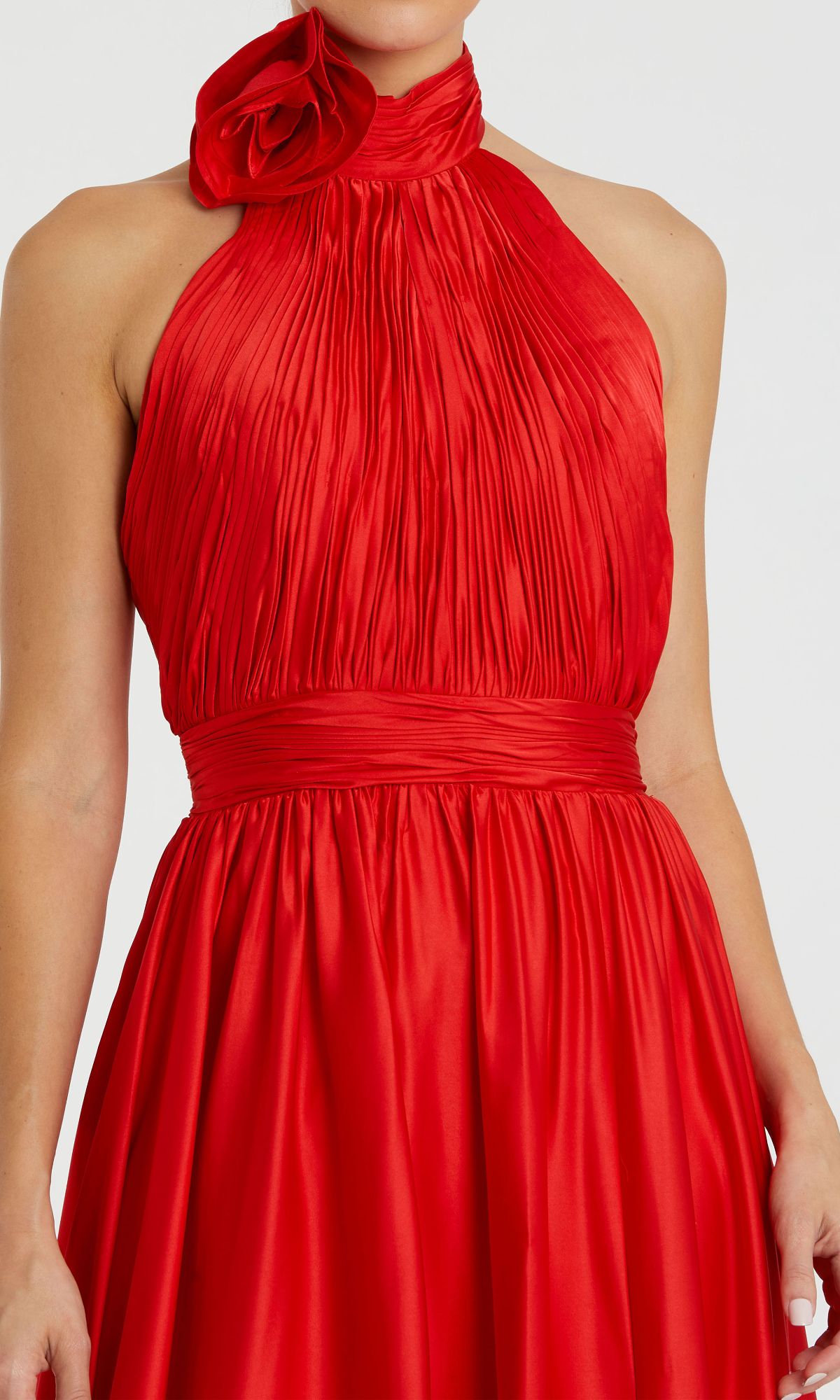 A woman wearing the Mac Duggal 49333 high-neck halter formal dress, a sleeveless, pleated red gown with a high neckline and a fabric rose detail at the neck.